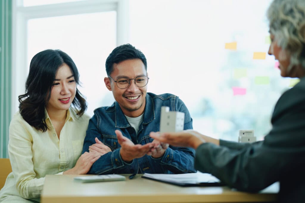 guarantee insurance sign a contract, couple a smiling couple is signing a contract to invest in real estate with the mortgage officer with the bank